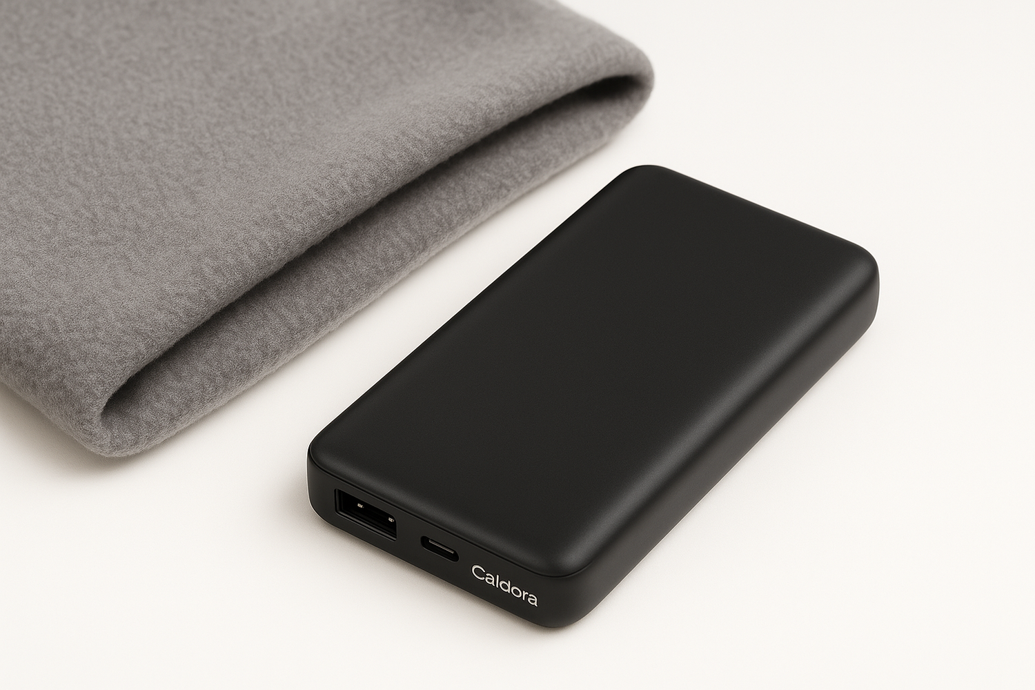 Caldora power bank placed next to folded heated shawl on white background for product bundle display